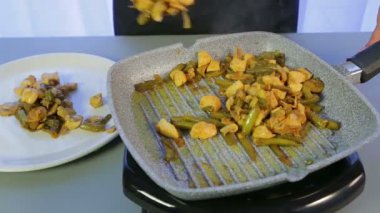 Bir kadın kızarmış tavuğu yeşil fasulye ve mantarla tavadan beyaz bir tabağa yerle bir ediyor..