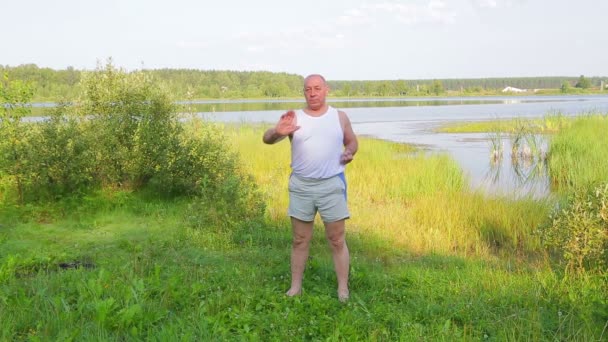 Ένας μεσήλικα άντρας αναπνέει γιόγκα στη λίμνη το πρωί. — Αρχείο Βίντεο