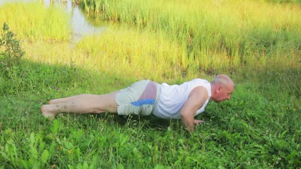 Mężczyzna w średnim wieku robi push-upy na jeziorze w godzinach porannych — Wideo stockowe