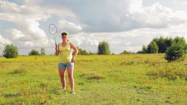 Žena na mýtině slouží a zasáhne míč, když hraje badminton — Stock video