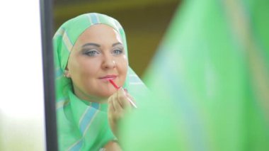 Müslüman kadın dudak kalemi ve kırmızı ruj uygular.