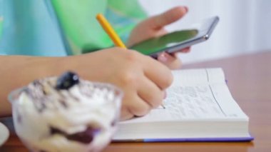 Kafedeki bir kadın uzaktan telefon ve günlükle çalışıyor.