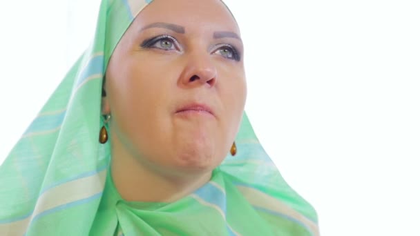 Een jonge moslim vrouw in een licht groene sjaal in een café eet taarten en drankjes thee — Stockvideo