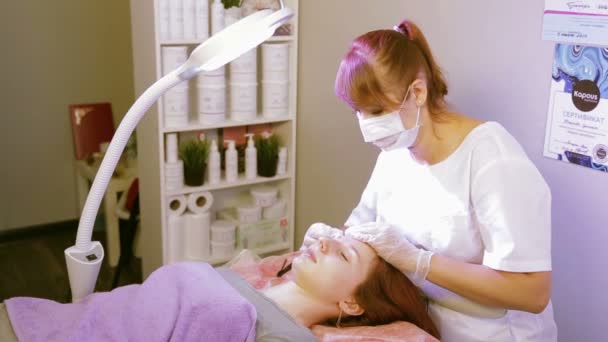 Den kosmetolog gnuggar klienterna ögonbryn med en desinfektionsmedel lösning innan korrigeringen — Stockvideo