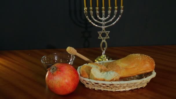 Challah, honey and pomegranate for the holiday of Rosh Hashanah next to the menorah with candles — Stock Video