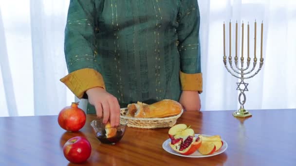 유대인 여자가 샬라 한 조각을 취하고 로쉬 하샤나를 위해 꿀에 담근다. — 비디오