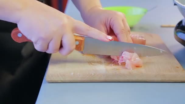 Жінка нарізає куряче філе ножем на дерев'яній дошці. Часові кола — стокове відео