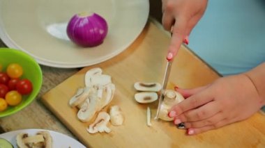 Bir kadın ahşap tahta üzerinde bir bıçak ile dilimleri içine champignon mantar pirzola. zaman Tur