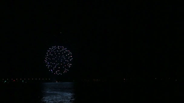 Brillantes fuegos artificiales festivos en el cielo nocturno sobre el río reflejándose en el agua. Vueltas de tiempo — Vídeos de Stock