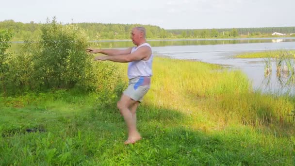 Homme âgé faisant des exercices d'étirement sur le lac le matin — Video