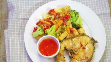 Izgara için maşa bir tavada sebze ve balık kavurma karıştırın