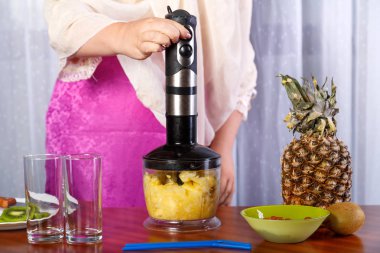 Kadın püre bir blender içinde ananas doğrar.