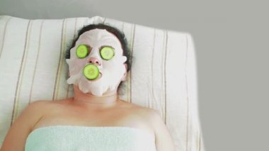 Bir erkek güzellik müşterilerinin yüzüne spa salonu taze salatalık koyar