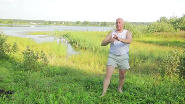 中年の男性は 午前中に湖でヨガや呼吸の練習をします 全体的な計画 — ストック動画