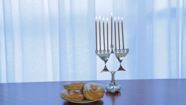 Χανουκά με κεριά και ένα πιάτο με ντόνατς στο τραπέζι — Αρχείο Βίντεο