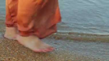 Geniş pantolon yalınayak Kadın bacaklar deniz suyu kenarı boyunca gitmek