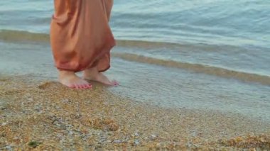 Geniş pantolon yalınayak Kadın bacaklar deniz suyu kenarı boyunca gitmek