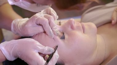 Beautician cımbız ile müşterilerin kaşları düzeltir.