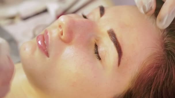 El esteticista lava la henna de las cejas del cliente y aplica una crema especial — Vídeo de stock