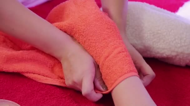 Косметолог надевает махровые перчатки на руки клиента во время парафиновой терапии рук — стоковое видео