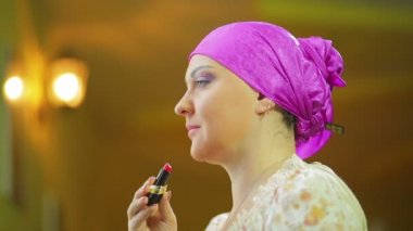 Bir ayna önünde evli bir Jewess kırmızı bir ponpon dudakları boyar