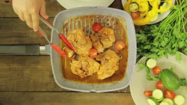 Dişi el ızgara tavada tavuk parçaları sebze koyar.
