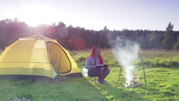 Žena poblíž šálu u ohně čte knihu — Stock video