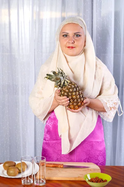 一位年轻的穆斯林妇女，手里拿着一个菠萝. — 图库照片