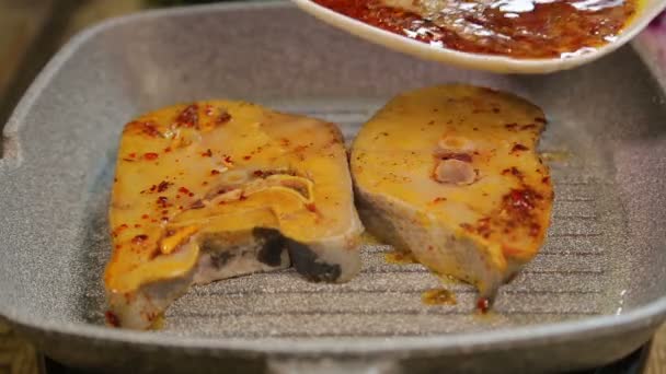 Una mano femenina está usando pinzas de pescado para asar pescado con una salsa de plato blanco — Vídeos de Stock