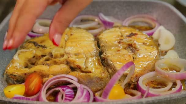 La mano femenina pone en el pescado cebollas en rodajas y anillos de tomate cherry . — Vídeos de Stock