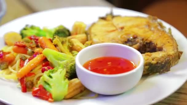 Тарелка с рыбой и спагетти с овощами и азиатским соусом вращается по кругу — стоковое видео
