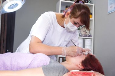 Usta kozmetolojist, istemcide kına kaşlarını lekeler.