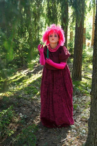年轻的女巫在森林里穿着紫色的衣服，手里拿着蜡烛. — 图库照片
