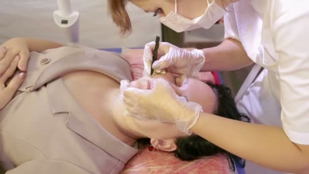 Косметолог вырывает волосы из верхней губы клиента — стоковое видео