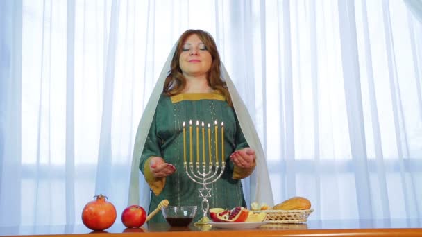 Єврейська жінка стоїть на святковий стіл з палаючою свічки напередодні Рош-Ха-Шана — стокове відео
