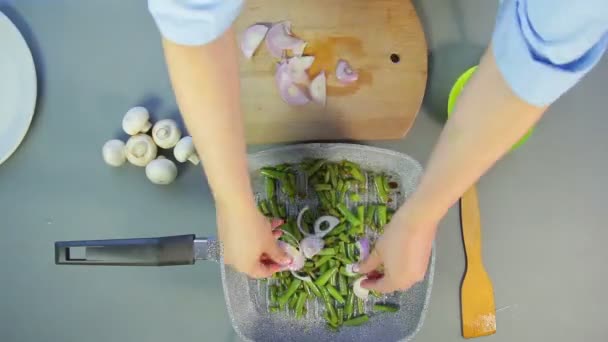 La mano femenina mezcla los frijoles en una sartén y corta los champiñones y las cebollas. Vueltas de tiempo — Vídeos de Stock