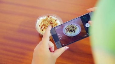 Kadın eller telefonu tutun ve kek fotoğraf çekmek.