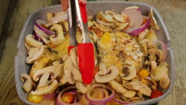 Female hand turns grilled fish steaks with tongs and mixes mushrooms with onions. time laps. — Stock Video