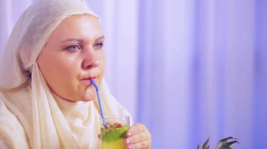 Hafif bir eşarp bir genç Müslüman kadın bir meyve smoothie içecekler ve gülümsüyor