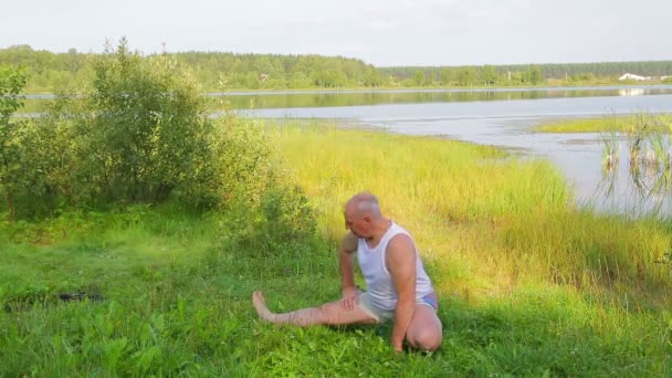 午前中に湖でストレッチエクササイズをしている中年男性 — ストック動画