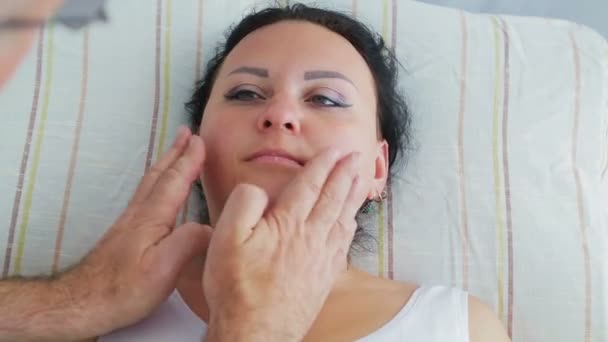 Un cosmétologue masculin donne à une femme un massage du visage tonifiant — Video