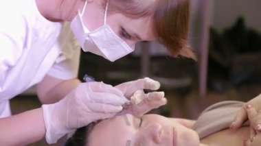 Beautician cımbız ile müşterilerin kaşları düzeltir.