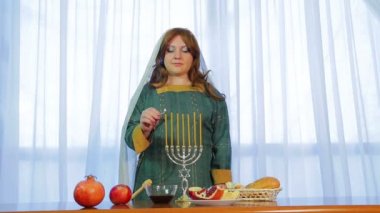 Bir Yahudi kadın davranır ile şenlikli partide Rosh Hashanah üzerinde güzel bir mum çubuğunda mumlar yanar
