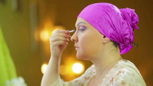 En gift Jewess gör makeup framför en spegel med ögonskugga — Stockvideo