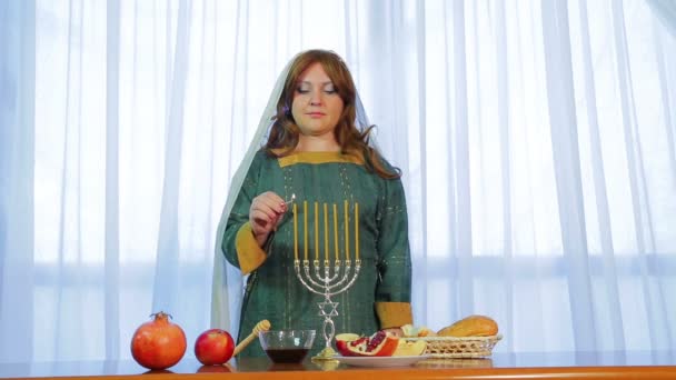 Еврейка зажигает свечи в красивом подсвечнике на Рош а-Шана на праздничной вечеринке с угощениями — стоковое видео