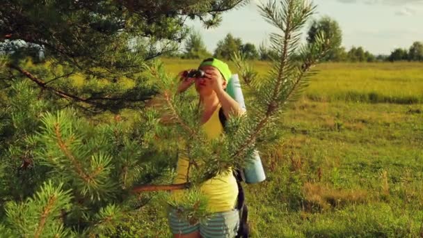 Kobieta turysta stoi w lesie polać i patrzy przez lornetki, gdzie pójść dalej. — Wideo stockowe