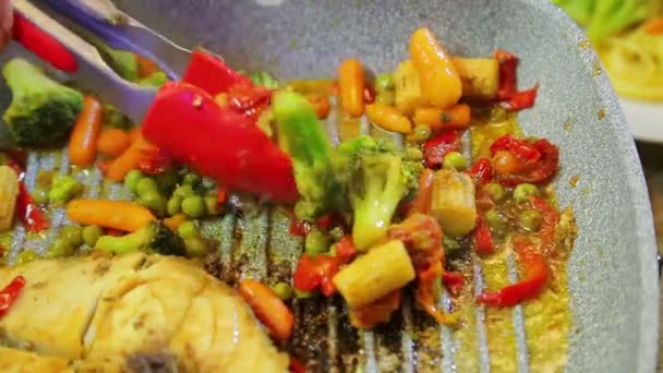 La mano femenina pone verduras en un plato con espaguetis y pescado . — Vídeos de Stock