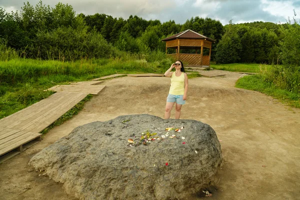 Touristin blickt durch Fernglas in der Nähe eines riesigen Steins. — Stockfoto