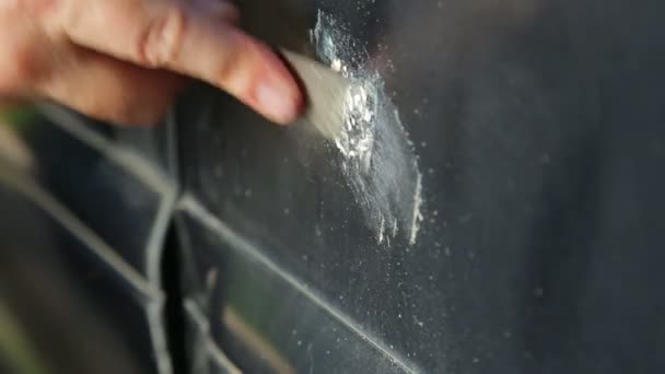 Um homem limpa a ferrugem num carro com um arranhão. — Vídeo de Stock