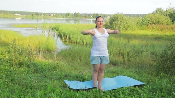 Mulher morena fazendo exercícios de alongamento no lago pela manhã — Vídeo de Stock